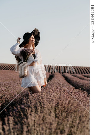 Woman in a White Dress and Black Hat Standing in a Lavender Field Woman in a White Dress and Black Hat Standing in a Lavender Field 128445391