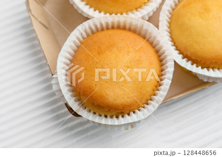 Vanilla muffins with paper cups in cardboard container. Top view 128448656