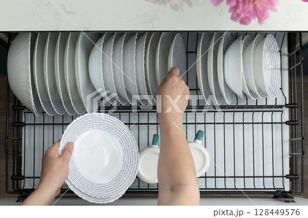Kitchen Activity Includes Loading Clean Dishes Into a Dishwasher in a Modern Home Setting 128449576
