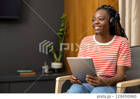 Young woman in headphones sitting at laptop and looking busy Young woman in headphones sitting at laptop and looking busy 128450060
