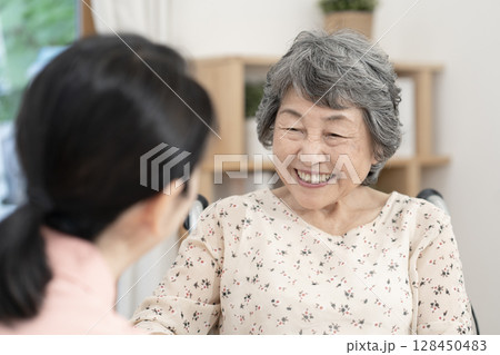 女性介護士と話をするシニア女性 128450483