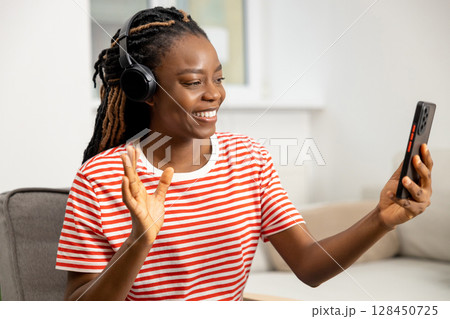 Smiling cute long-haired african american young woman working online Smiling cute long-haired african american young woman working online 128450725