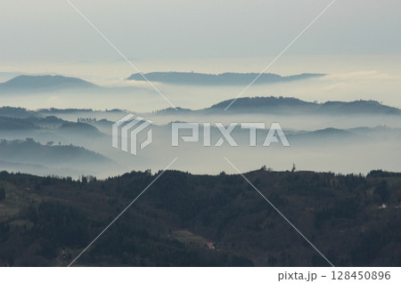 a mysterious landscape of mountains shrouded in fog and towering over the Mummelsee in Germany 128450896