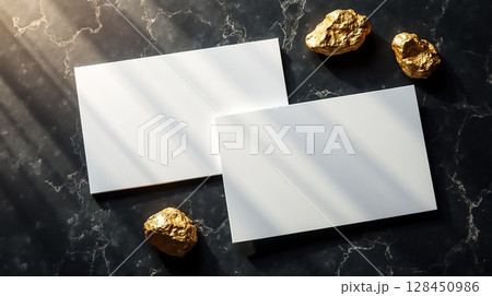 Clean white cards with gold accents resting on a dark marble surface illuminated by natural light Clean white cards with gold accents resting on a dark marble surface illuminated by natural light 128450986