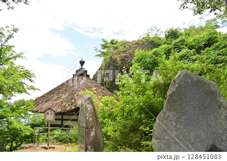 新緑の木々に囲まれた茅葺屋根の長楽寺観音堂とバックの姨石 128451083