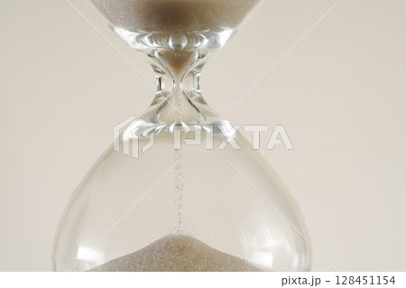 A minimalist conceptual image of an hourglass to symbolize the passage of time, aging, and importance of skincare, balance. 128451154