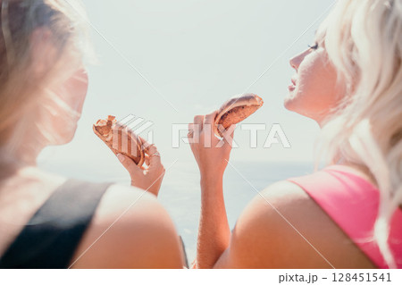 Two Blonde Women Enjoying a Snack on a Sunny Day 128451541