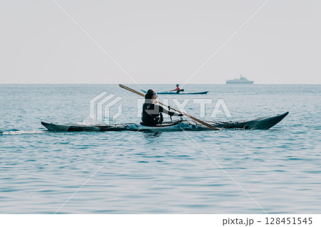 Kayaking Water Sport Ocean - Person kayaking in ocean with paddle, enjoying water sport on a misty day. 128451545
