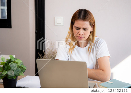Unhappy young caucasian businesswoman using laptop computer on desk with stress and burnout. Unhappy young caucasian businesswoman using laptop computer on desk with stress and burnout. 128452131