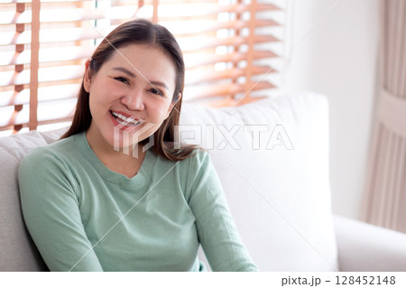 Portrait young asian woman expression and emotion with laughing sitting on sofa with cozy. 128452148