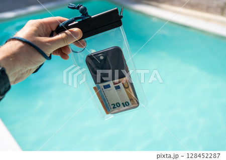 Waterproof case with money and a smartphone on the background of the pool on a sunny summer day Waterproof case with money and a smartphone on the background of the pool on a sunny summer day 128452287