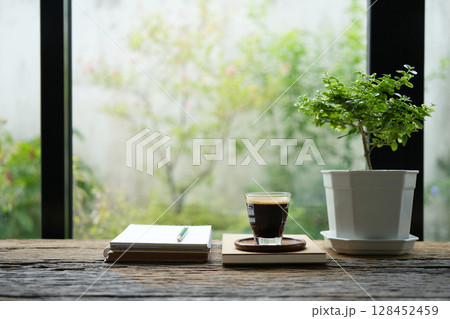 Coffee mug and notebook and plant by the window Coffee mug and notebook and plant by the window 128452459