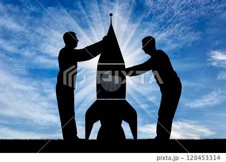 Silhouettes of two men collect a rocket Silhouettes of two men collect a rocket 128453314