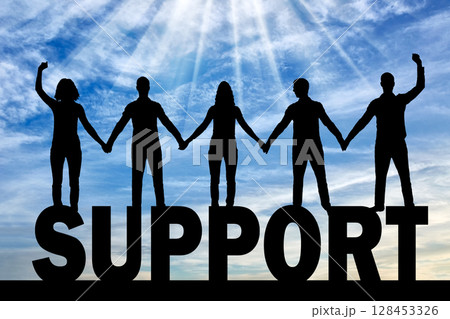Silhouette of a group of happy people of five people holding hands while standing on a word of support 128453326