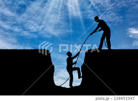 A silhouette of a man helps to get out of the pit to another. A silhouette of a man helps to get out of the pit to another. 128453347