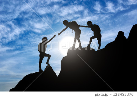 Silhouette of two female mountaineers helping another female mountaineer to overcome the obstacle in the mountains Silhouette of two female mountaineers helping another female mountaineer to overcome the obstacle in the mountains 128453376