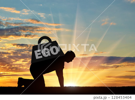 The silhouette of an egotistic man who crawls, it's hard for him, on his back a heavy load - ego. 128453404