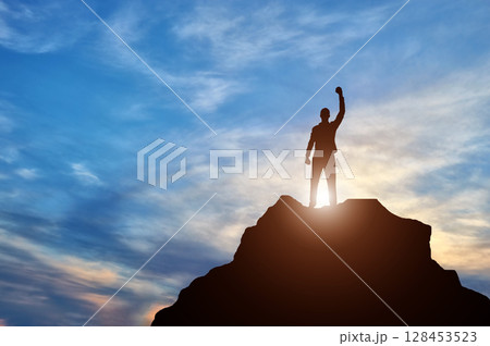 Silhouette of a happy climber on top of a mountain which he conquered Silhouette of a happy climber on top of a mountain which he conquered 128453523