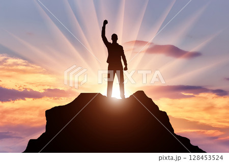 Silhouette of a happy mountaineer on top of a mountain 128453524