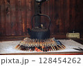 囲炉裏で焼かれる串刺しの川魚と鉄瓶 128454262