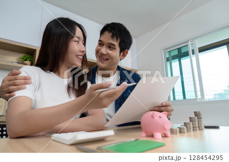 Couple Financial Planning. Young partners discussing savings and investments with piggy bank. 128454295