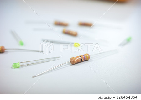 Close-up of electronic components on a white surface, including resistors and LEDs 128454864