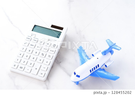 電卓と飛行機で、高騰する航空券代と、高騰する旅行代金のイメージ 128455202
