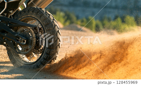 Flying rocks and dust from the wheel of a motocross bike at the start of the race Flying rocks and dust from the wheel of a motocross bike at the start of the race 128455969