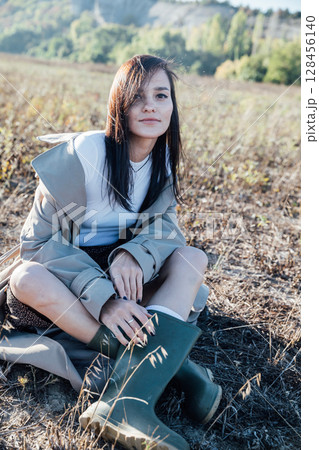 Beautiful brunette woman in sitting on an autumn field Beautiful brunette woman in sitting on an autumn field 128456140