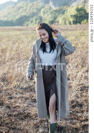 Beautiful woman in a coat walking in an autumn field 128456152
