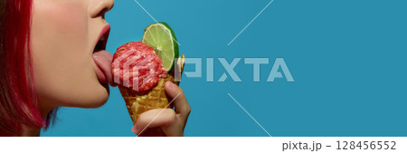 Woman licking meatball ice cream in cone with lime slice on turquoise background. Banner 128456552