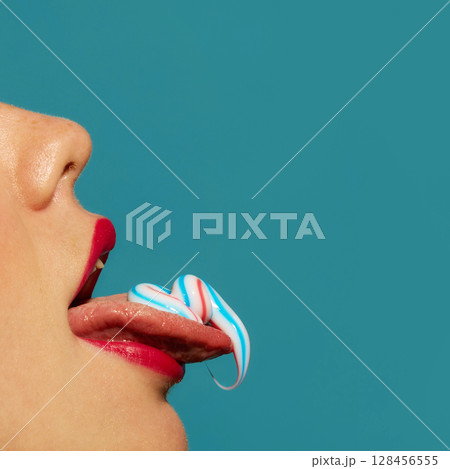 Red lips licking toothpaste from tongue with playful expression on turquoise background Red lips licking toothpaste from tongue with playful expression on turquoise background 128456555