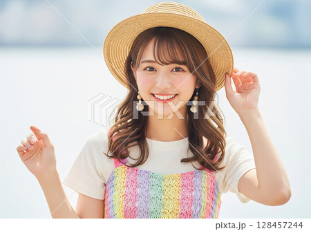 夏を彩るファッション！カラフルなサマーニット：麦わら帽子を被り爽やかな笑顔を見せる日本人女性モデル 128457244