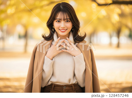 秋の装い！笑顔輝くキャメルコートとタートルネックの女性 128457246