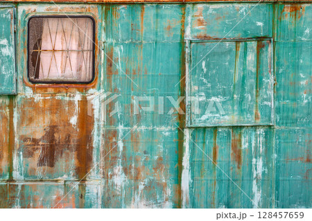 Rusty green metal wall with window and door in industrial setting 128457659
