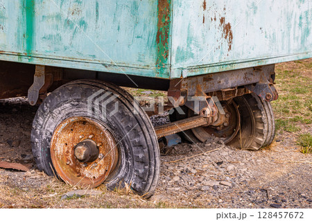 Rusty old trailer with partially visible wheels in rural setting 128457672