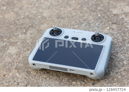 Drone remote control lying on concrete surface outdoors during daytime Drone remote control lying on concrete surface outdoors during daytime 128457724