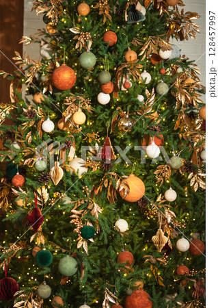 Merry Christmas Xmas happy holidays. Golden ornament decoration ball and defocused garland lights on classic decorated Christmas tree. Christmas tree with brown ornaments. Christmas eve at home Merry Christmas Xmas happy holidays. Golden ornament decoration ball and defocused garland lights on classic decorated Christmas tree. Christmas tree with brown ornaments. Christmas eve at home 128457997
