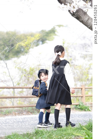 桜と入園式を迎えた3歳の女の子と9歳の姉 128458261