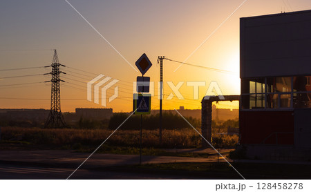 A road sign and other infrastructure in the light of the setting sun 128458278