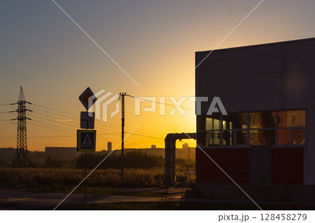 A road sign and other infrastructure in the light of the setting sun 128458279