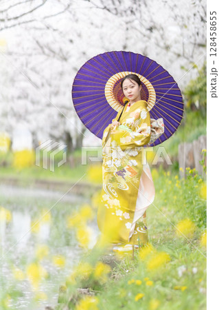 満開の桜を振袖で歩く若い女性 128458655