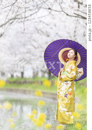 満開の桜を振袖で歩く若い女性 128458658