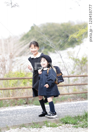 桜と入園式を迎えた3歳の女の子と9歳の姉 128458777