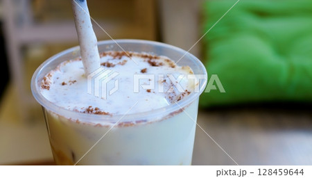 Skilled barista layering whipped cream and cocoa powder on chilled coffee, crafting gourmet summer beverage at modern cafe counter Skilled barista layering whipped cream and cocoa powder on chilled coffee, crafting gourmet summer beverage at modern cafe counter 128459644