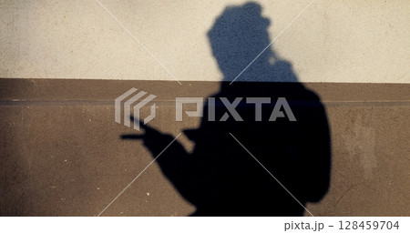 Silhouetted female shadow creating peace sign gesture on minimalist two tone wall, repeating symbolic hand movement with stylish, playful energy Silhouetted female shadow creating peace sign gesture on minimalist two tone wall, repeating symbolic hand movement with stylish, playful energy 128459704
