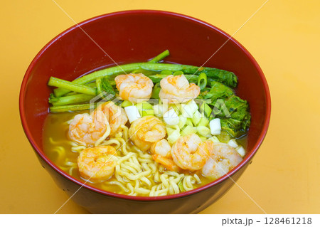 A close up of a vibrant bowl of ramen featuring noodles, succulent shrimp, crisp green vegetables, and chopped green onions in a rich, savory broth. A close up of a vibrant bowl of ramen featuring noodles, succulent shrimp, crisp green vegetables, and chopped green onions in a rich, savory broth. 128461218