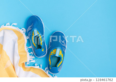 Water shoes and a striped towel on a blue background. Water shoes and a striped towel on a blue background. 128461762