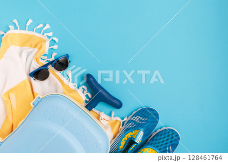 Children's beach essentials including  sunglasses, water shoes, suitcase and towel. 128461764