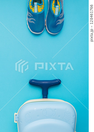 Water shoes and a child's suitcase on a blue background. Water shoes and a child's suitcase on a blue background. 128461766